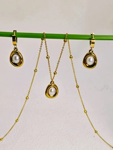 Detail of gold pearl jewelry set hanging on a green stem with necklace and earrings
