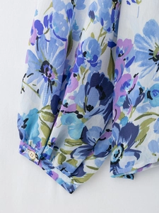 Detailed view of the blue floral print on chiffon fabric showing cuffs and hemline detail