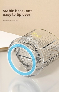 Close-up of a striped transparent makeup brush holder with a stable blue base design
