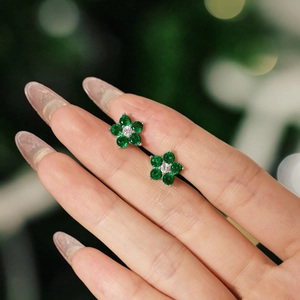 Gros plan de boucles d'oreilles fleurs vertes avec zircons sur base argentée
