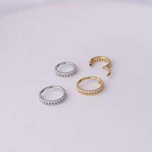 Detailed view of gold and silver stainless steel hinged rings with zircon and bead accents