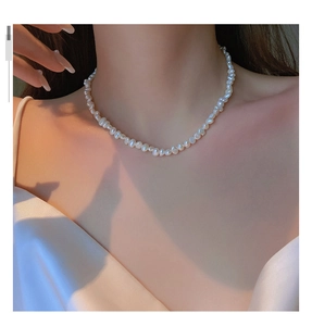 Elegant baroque freshwater pearl necklace worn by a model on a white dress