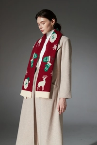 Detail of red Christmas knit scarf featuring white reindeer and snowflake festive patterns