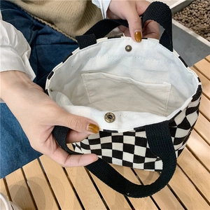 Detail of corduroy checkerboard tote bag showing metal snap button and inner pocket