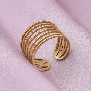 Detail of a multilayered matte gold open ring on elegant purple silk fabric