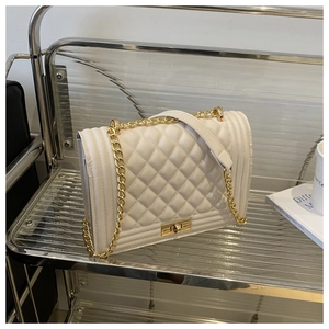 Detailed macro of white quilted faux leather cross-body bag with golden chain and lock