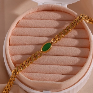 Detail of 18K gold plated Cuban chain necklace with an oval green gemstone pendant