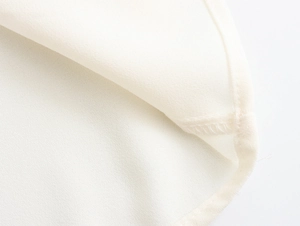Close-up of white chiffon fabric showing high-quality stitching and fine textile texture