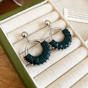 Detailed view of vintage green enamel and silver round earrings in a jewelry box