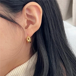 Close-up of a gold knot earring with Mobius design worn by a model on the ear