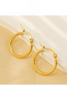 Detailed close-up of gold titanium steel hoop earrings with elegant spiral twist pattern