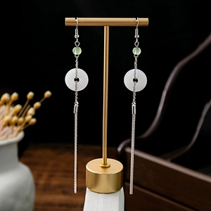 Detail of long tassel earrings with white jade circle and elegant silver metal fringe