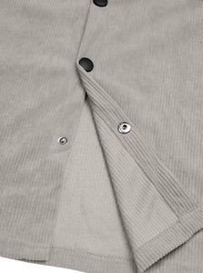Close-up of grey corduroy fabric texture and black metal snap buttons on the shirt
