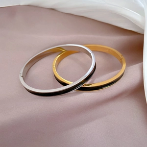 Minimalist gold and silver titanium steel bangles with black enamel inlay in a soft silk setting