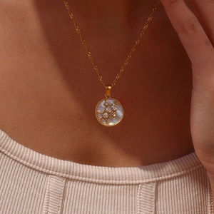 Close-up of mother of pearl round pendant necklace with gold sun and star motifs