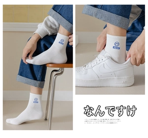 Detail of white cotton crew socks with blue smiley face embroidery and NICE text