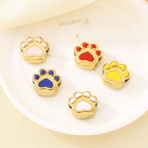 Colorful enamel cat paw charms in stainless steel displayed on a ceramic dish for DIY jewelry