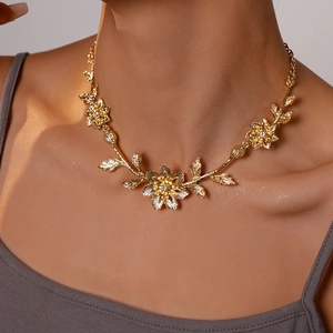Detailed view of a gold floral necklace featuring sparkling crystals and leaf patterns