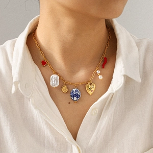 Golden stainless steel necklace with heart, baroque pearl, and shell charms on model