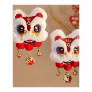 Close-up of embroidered Chinese lion hair clip with festive red pompom and golden bell
