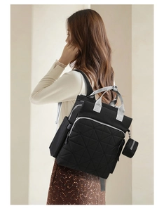 Detail of black quilted diaper backpack featuring grey handles and matching coin purse