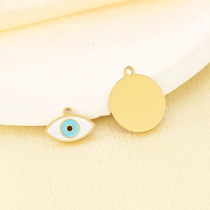 Detail of 18K gold stainless steel evil eye pendant on a smooth beige silk background