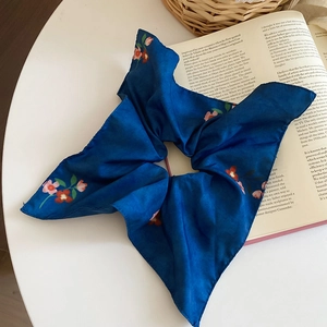 Close-up of floral print blue silk scrunchie with large bow on vintage book pages