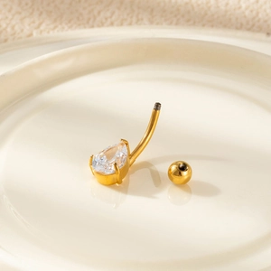 Macro shot of gold-plated navel ring with pear-shaped zircon on a ceramic tray