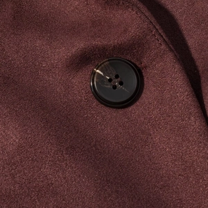 Macro shot of faux suede jacket with dark burgundy fabric and marble pattern button