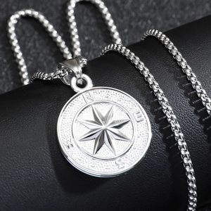 Polished silver stainless steel compass pendant necklace on black leather background
