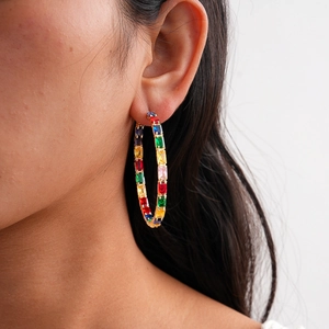 Close-up of a large gold hoop earring set with baguette-cut rainbow cubic zirconia stones
