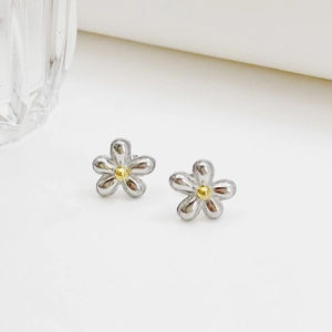 Polished silver five-petal flower earrings with golden core on a minimalist background