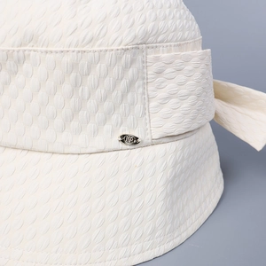 Macro detail of beige bucket hat featuring embossed texture and a small metal MR emblem