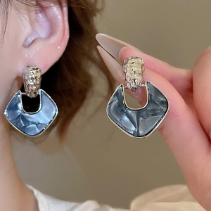 Detail of silver needle earrings with grey marble acrylic rhombic pendants and metal texture