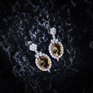 Close-up of S925 silver drop earrings featuring oval yellow gemstones and zircon pavé