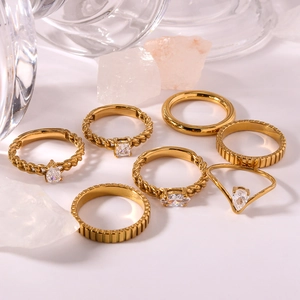 Set of 7 gold geometric stainless steel rings with zircon stones on white display