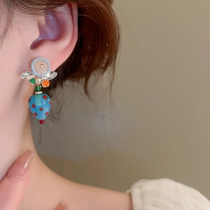 Close-up of blue strawberry-shaped glass earring worn by model showing sweet style