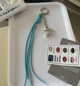 Detail of silver star metal keychain with long light blue braided lanyard and metal ring