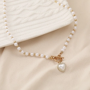 Detail of pearl necklace featuring heart pendant with micro-inlaid crystals and OT buckle