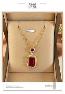 Close-up of gold titanium necklace with a square red gemstone pendant in jewelry box