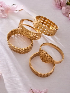 Detail of five-piece gold hollow textured wide bangles with intricate floral patterns