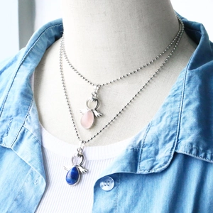 Detail of layered angel pendants with pink quartz and lapis stone on ball chains
