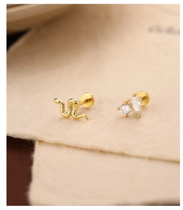 Macro view of gold s925 silver earrings with snake texture and clear zircon stones