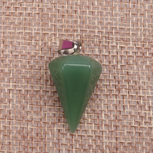 Macro shot of faceted green crystal pendulum pendant on rustic burlap background texture
