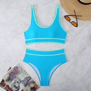 Blue bikini set with mint green trim on white marble background with summer props