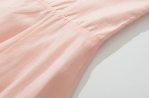 Detailed close-up of light pink sleeveless dress showing soft fabric texture and stitching