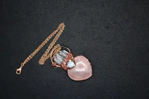 Macro detail of heart-shaped rose quartz pendant with vintage copper wire wrapping