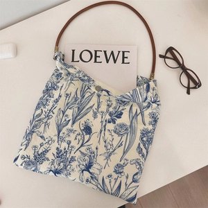 Detail of vintage blue floral canvas tote bag with brown leather handle and metal snap button