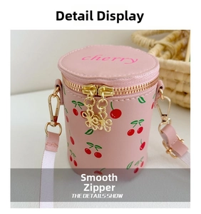 Detail view of pink cherry bucket bag with dual gold zippers and floral pullers