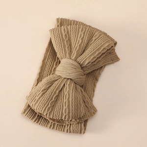 Detailed close-up of khaki knit baby headband with large bow and cable stitch texture